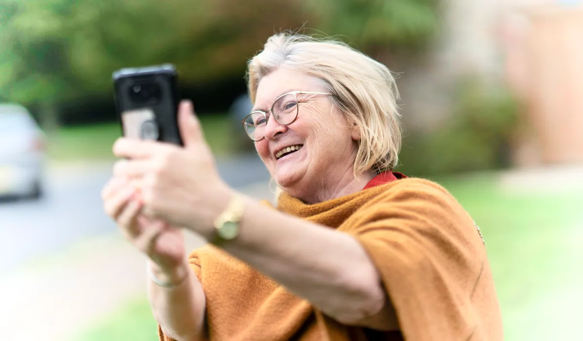 kvinna i övre medelåldern tar selfie med mobiltelefon